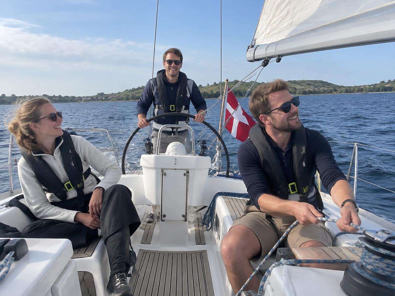 Kolleger i redningsveste nyder en sejltur, én står ved rattet